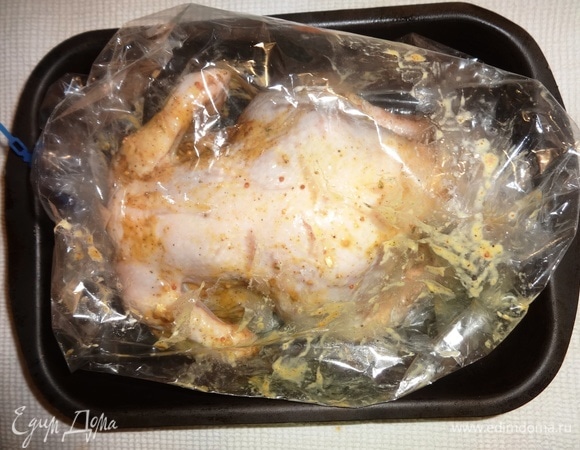 Достать курицу из холодильника. Нафаршировать дольками цитрусовых. Положить курицу в рукав для запекания. Концы рукава подвернуть и завязать. Сделать несколько проколов в верхней части рукава. Поставить курицу в духовку, разогретую до 180°C, на 30–35 минут.