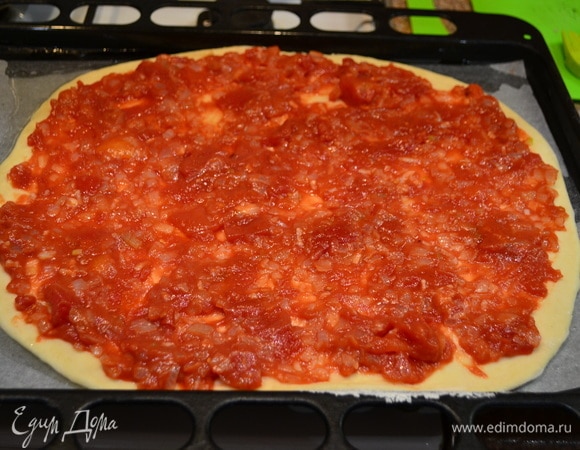 Тесто раскатать и переложить на противень, смазать смесью нарезанных помидоров в собственном соку с луком.