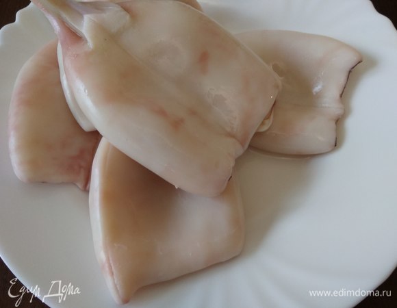 Тушки кальмаров очистить от пленок и прокипятить в подсоленой воде с лавровым листом и душистым горошком по 10 секунд каждую. Мантию отрезать, оставив только «носочек».