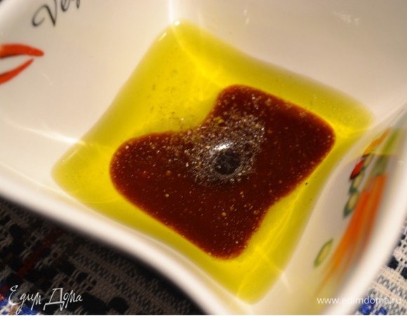 Готовим заправку. Гранатовый сироп добавляем в емкость. К нему добавим оливковое масло. Солим и перчим по вкусу. Взбиваем вилкой нашу заправку. Если у вас нет гранатового сиропа, его можно приготовить из сока, добавив сахар и выпарив его до состояния сиропа.