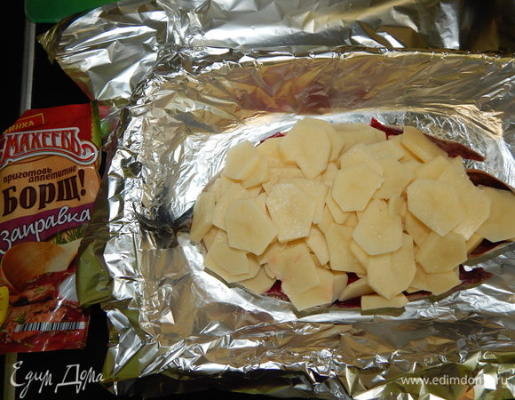 Картофель почистить и нарезать тонкими кружочками, уложить поверх скумбрии, посолить.