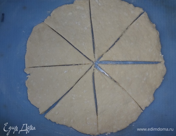 Разделить тесто на 2 части. На посыпанном мукой силиконовом коврике раскатать круг толщиной примерно 0,5 см. Разрезать круг на 8 сегментов.