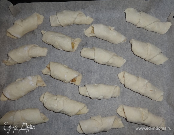 Противень застелить пекарской бумагой и выложить на нее рогалики. Противень поставить в духовку, разогретую до 190°C, на 25–30 минут. Рогалики должны слегка зарумяниться.