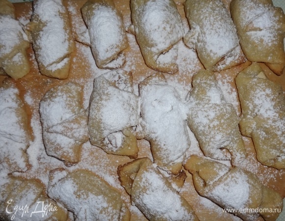 Снять рогалики с противня, выложить на доску и посыпать сахарной пудрой.