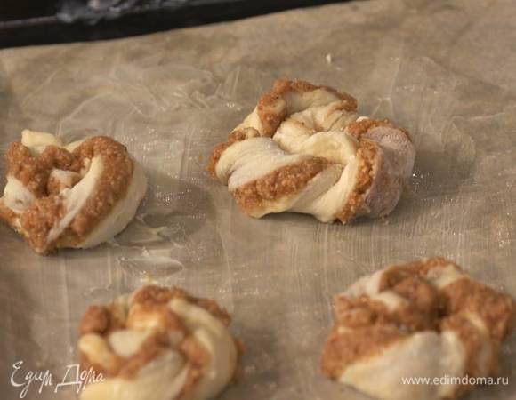 Выстелить противень бумагой для выпечки, смазанной оставшимся сливочным маслом, и выложить плюшки.