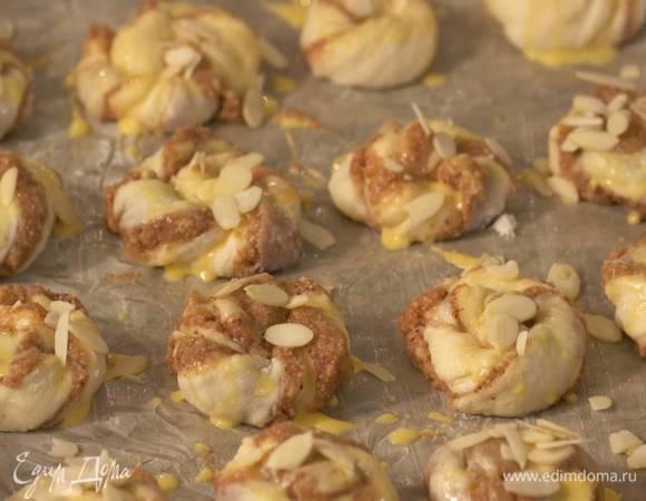 Оставшееся яйцо развести с молоком и смазать плюшки, посыпать миндальными лепестками и выпекать в разогретой духовке 15–20 минут.