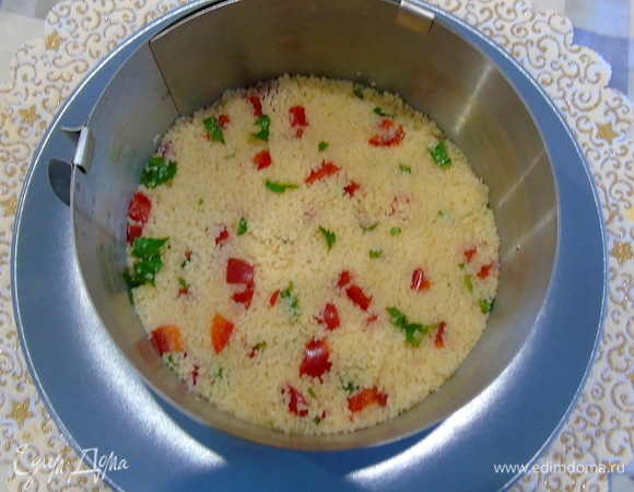 Салат собирайте в кольце диаметром 16 см. Положите кольцо на тарелку, выложите первый слой (кускус) и слегка утрамбуйте.