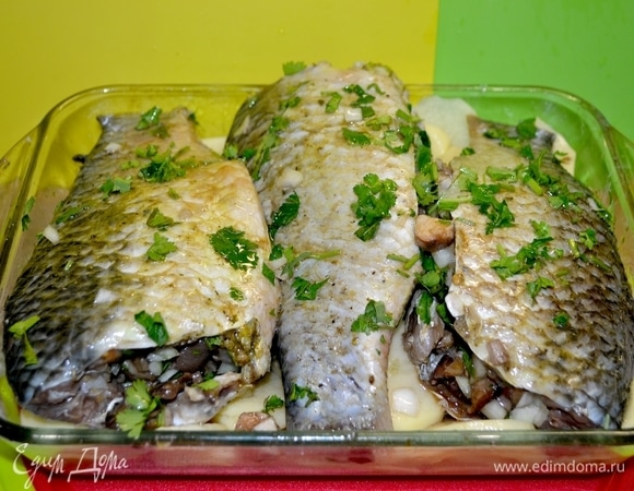 Сверху картошки положить грибы и нафаршированного карпа, добавить немного воды. Накрыть фольгой и отправить в духовку при 180–200°C до готовности.