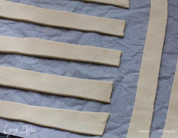 Полоски из теста переложить на противень, застеленный бумагой для выпечки, и выпекать в разогретой до 200°C духовке до золотистого цвета.