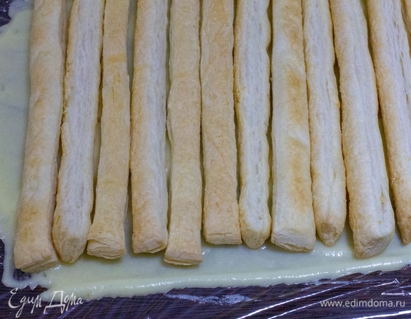 На рабочей поверхности расстелить фольгу или пищевую пленку, смазать ее кремом, на крем выложить рядом друг с другом первый слой трубочек. Смазать их кремом, затем сверху положить следующий слой трубочек и снова крем. И так, пока не закончатся все трубочки.