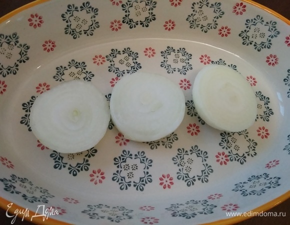 На дно формы для запекания положим очищенную луковицу. Я разрезала ее на три части. Лук придаст нашему кушанью аромат и поможет мясу правильнее приготовиться.