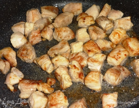 В сковороду налить половину масла и разогреть его. Выложить кусочки свинины и обжарить их на сильном огне до румяной корочки. Выложить мясо в кастрюлю, оставив масло в сковороде.