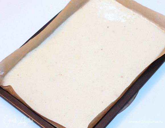 Противень застелить пекарской бумагой, немного смазать маслом и вылить тесто, затем аккуратно распределить его по всей форме и сразу же отправить выпекаться в заранее разогретую до 180–190°C духовку.