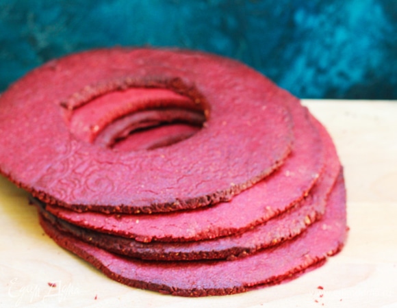 Тесто вынуть, разделить на 4 части и раскатать коржи диаметром чуть больше 20 см. Внутри вырезать кружок вырубкой около 10 см или меньше. Тесто раскатывать между двумя листами пергамента. Остальное тесто положить обратно в холодильник. Остатки раскатать фигурной скалкой, вырезать печенье для декора, смазать с помощью сухой кисти кандурином. Выпекать при температуре 180°C 7–9 минут. Коржи сложить стопкой и оставить до полного охлаждения.