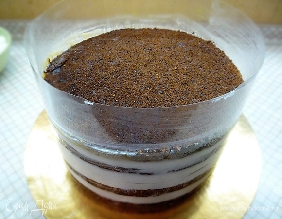 Собираем торт в кольце. Кольцо выстилаем ацетатной пленкой, первым выкладываем диск бисквита, затем тонким слоем — крем. Поверх крема наливаем половину карамели, затем выкладываем второй бисквит, смазываем тонким слоем крема, поверх крема выкладываем апельсиновую прослойку, затем опять смазываем кремом. На крем выкладываем третий бисквит, смазываем кремом, на крем выливаем вторую половину карамели, равномерно распределяя ее. Поверх карамели выкладываем четвертый бисквит. Убираем торт на ночь в холодильник.