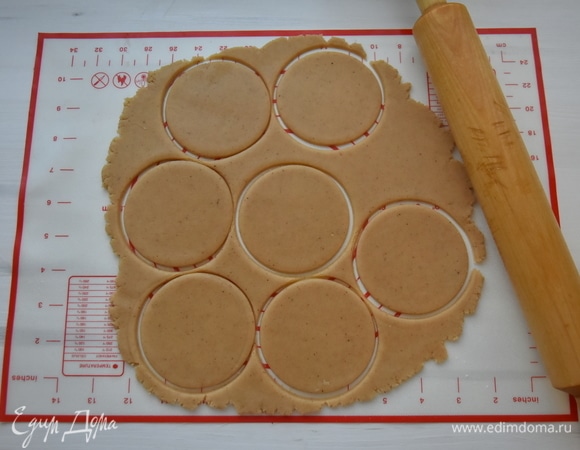 Разделить тесто на две части. Одну оставить в холодильнике. Другую раскатать в пласт толщиной 0,5 мм. Стаканом или формой вырезать кружочки. Выпекать печенье 7 минут в духовке, разогретой до 180°C. Дать печенью остыть, разложив его в один слой на поверхности.