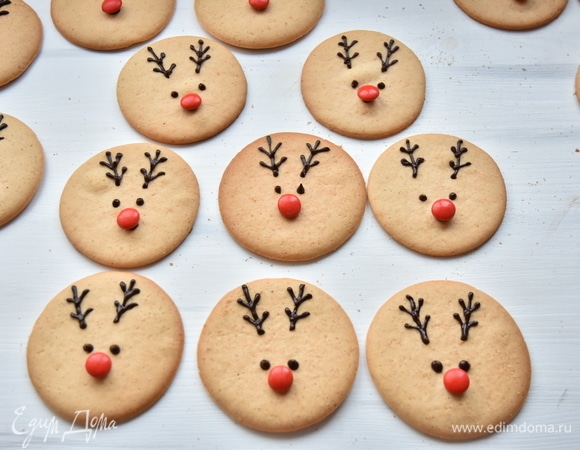 На каждой печеньке оформить мордочку олененка, закрепив носик из конфеты с помощью шоколадной капли. Также оформить глазки и рожки. Эту творческую процедуру можно поручить детям.