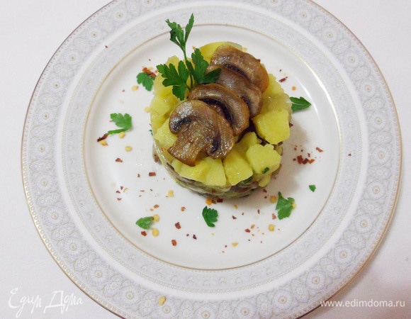 Выложить салат через кулинарное кольцо, украсить ломтиками грибов и зеленью.