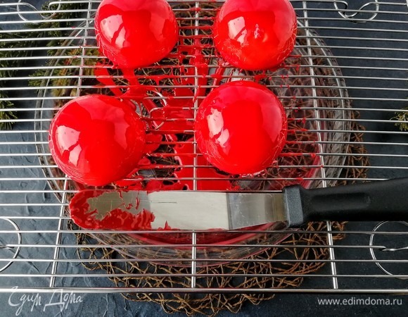 Поливаем глазурью ровно посередине. Физика сделает свое дело, глазурь сама растечется по всему пирожному. Когда излишки глазури стекут, удалите висячие красные нити с помощью спатулы, подвигав аккуратно пирожные по решетке. Теперь даем пирожному растаять.