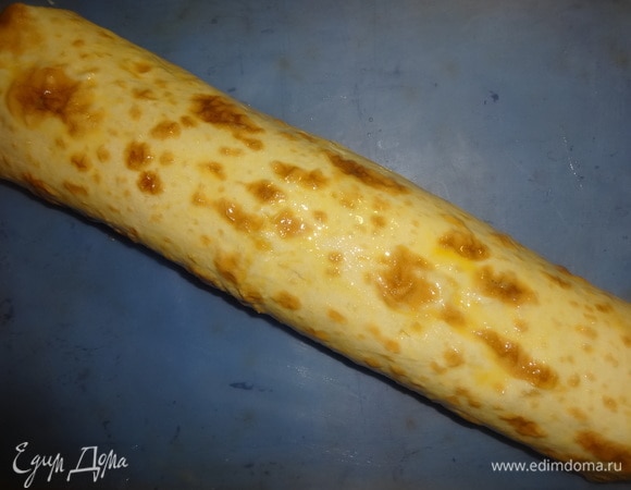 Свернуть рулет полностью и еще раз смазать всю поверхность яйцом. Поставить противень с рулетом в духовку, разогретую до 180°C, на 8–10 минут.