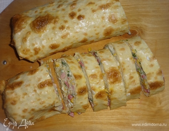 Горячий рулет выложить на доску и разрезать на кусочки ножом с зубчатыми краями.