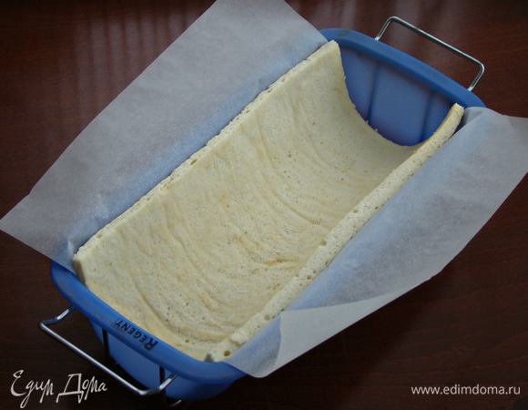 Форму выстлать пекарской бумагой и уложить бисквит.