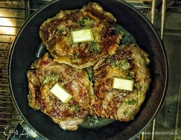 Сверху на каждый стейк положим по кусочку сливочного масла, накроем горячую сковороду фольгой и поставим в духовку на 7 минут.