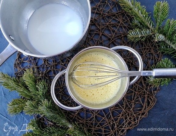 Теперь один из самых ответственных шагов: темперирование желтков. Для этого мы сначала тонкой струйкой вливаем немного молока к желткам, интенсивно помешивая массу венчиком. Добавляем еще немного. Когда перельем, мешая, половину молока, можно желтково-молочную смесь вливать к оставшемуся молоку. Также перемешиваем и ставим на средний огонь, а лучше — на водяную баню, так меньше шансов проморгать «час икс». Кипящая вода в таком случае не должна касаться чаши. Варим крем, постоянно мешая силиконовой лопаткой, до тех пор, пока он не станет густеть или до 80°С. Если вдруг увидите, что начали образовываться хлопья, быстро снимайте сотейник с огня и ставьте его в чашу с ледяной водой, интенсивно мешая крем. В таком случае его еще можно будет спасти, процедив через мелкое сито. Если же появился устойчивый привкус яиц и много хлопьев, то, к сожалению, крем уже не реанимировать. Поэтому будьте внимательны.