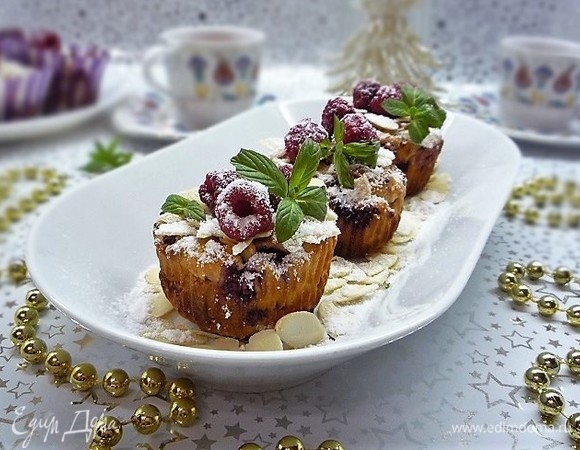 Даем маффинам немножко остыть, украшаем ягодками малины, листиками мяты. Посыпаем сверху сахарной пудрой и лепестками миндаля. Лепестки миндаля можно слегка обжарить на сухой сковороде.