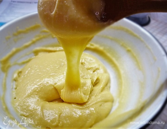 Приготовим профитроли. В кастрюльку вливаем молоко и воду, добавляем нарезанное небольшими кубиками сливочное масло, щепотку соли, сахар, ставим на средний огонь и даем закипеть. Всыпаем всю муку (150 г), убираем огонь до минимума и мешаем тесто, собирая его в большой шар, примерно 5–7 минут. Перекладываем тесто в чистую чашку, даем немножко остыть и добавляем яйца, по одному, небольшими порциями, постоянно мешая миксером или руками. У меня ушло 4 больших яйца. Готовое тесто должно сползать тяжелой широкой лентой (треугольником).