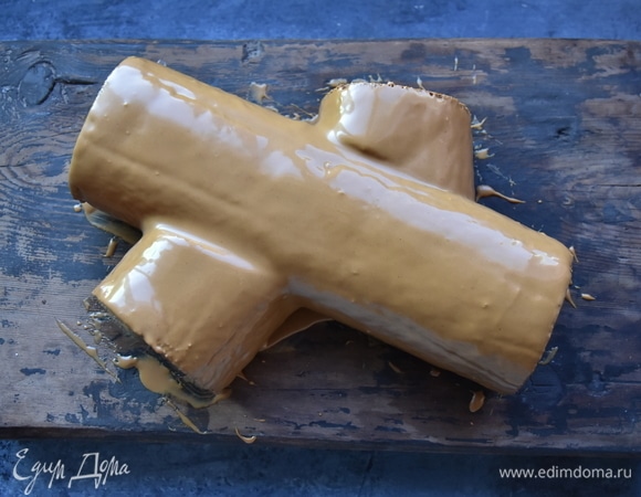 Отрезать с двух сторон небольшие кусочки. Приложить их с обоих краев рулета, имитируя сучки дерева. В оставшийся крем добавить 1 ст. л. с горкой какао-порошка. Крем взбить до однородного цвета и промазать им сформированный торт. Оставить торт до застывания крема в прохладном месте. Поверх крема с помощью вилки или деревянной шпажки нанести узор, имитирующий кору дерева. Сверху торт посыпать какао-порошком и сахарной пудрой. Украсить торт по желанию.