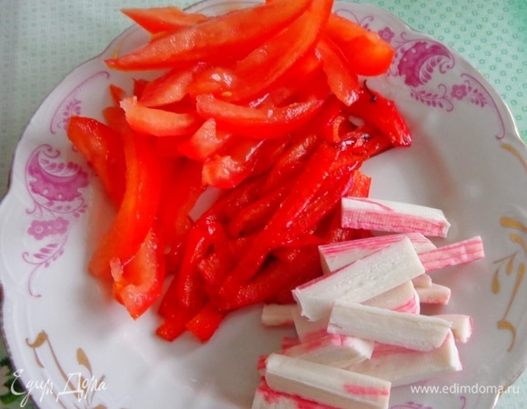 Красный болгарский перец нарезать тонкими пластинками и слегка обжарить. Помидор освободить от семян и лишней жидкости и нарезать пластинками. Такими же пластинками нарезать крабовые палочки.