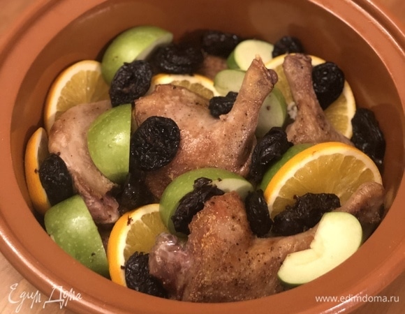 В форму для запекания выложите утиные ножки, апельсины, яблоки и чернослив.