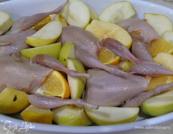 Разрезаем второй апельсин на дольки и каждую дольку вставляем во внутрь тушки. Выкладываем в форму в которой будем запекать. Вокруг перепелок выкладываем нарезанные дольками яблоки и айву.