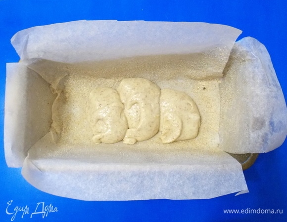 Прямоугольную форму застелить бумагой для запекания. Смазать ее маслом и обсыпать сухарями. Положить на дно 3 ст. л. теста и разровнять.