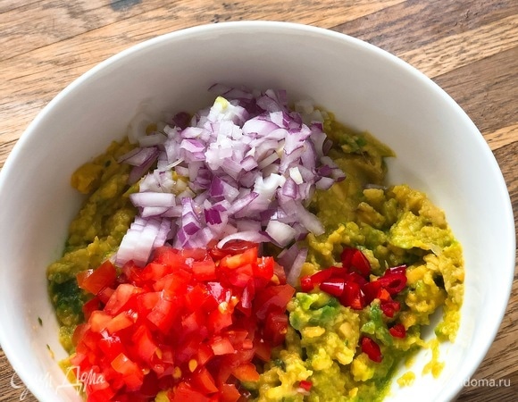 К пюре из авокадо добавить мелко нарезанный лук, помидор и перец чили.