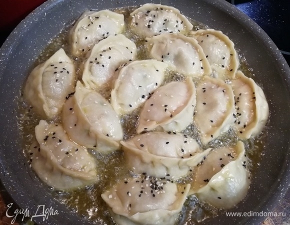 Вливаем 2 ст. л. кунжутного масла, посыпаем гедза кунжутом и жарим еще около 2 минут.