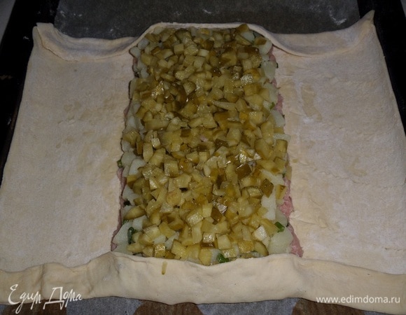 Поверх картофеля выкладываем нарезанные маринованные огурцы, равномерно распределяем. Подгибаем края пласта теста сверху и снизу.