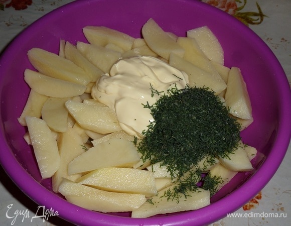 Картофель нарезаем дольками. Выкладываем в глубокую чашку нарезанный картофель, половину приготовленного майонеза и 1 ст. л. нарезанного укропа (я использовала замороженный укроп из собственных заготовок).
