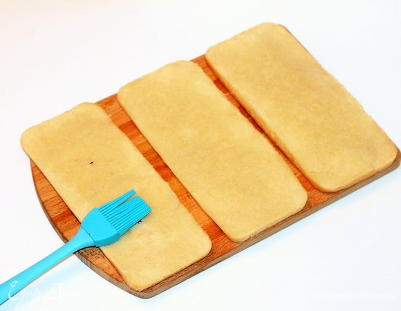 Разрезать бисквит горизонтально на 3 коржа. Если у вашего бисквита при выпечке появилась верхушка, ее можно срезать. Обрезки подсушить на сухой сковороде и измельчить в крошку, а затем применить для украшения торта. Для сиропа смешать воду и сахар, довести до кипения, дать остыть и влить коньяк или вино. Пропитать коржи сиропом и дать время пропитаться, минут 20.