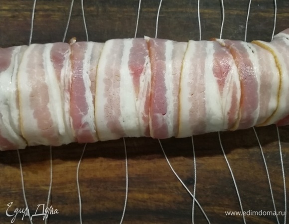 На разделочную доску выкладываем полоски кулинарной нити, затем наш рулет и обвязываем.