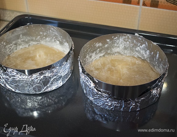 Для выпечки коржей необходимы кольца или другие имеющиеся формы диаметром 16 см. Если используете кольца, то необходимо обтянуть их фольгой. Стенки форм смазать сливочным маслом и обсыпать мукой, лишнюю муку стряхнуть, а дно застелить бумагой для выпечки. Всего будет 4 коржа. Выпекать можно в два приема.