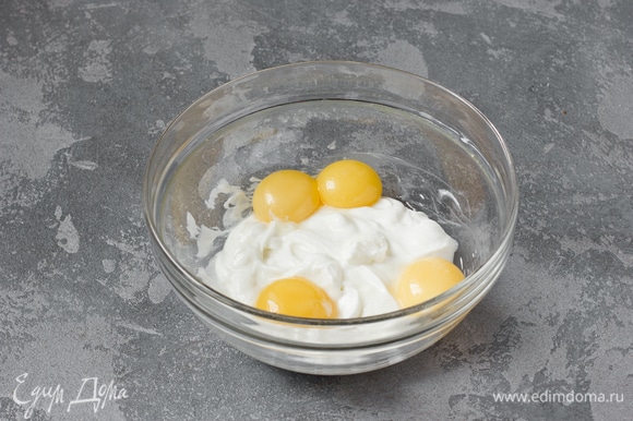 После того как сыворотка стечет, в марле должно остаться 220 г густой йогуртовой массы. Переложить ее в глубокую миску. Добавить туда же 40 г сахара и яичные желтки, перемешать силиконовой лопаткой до получения однородной массы.