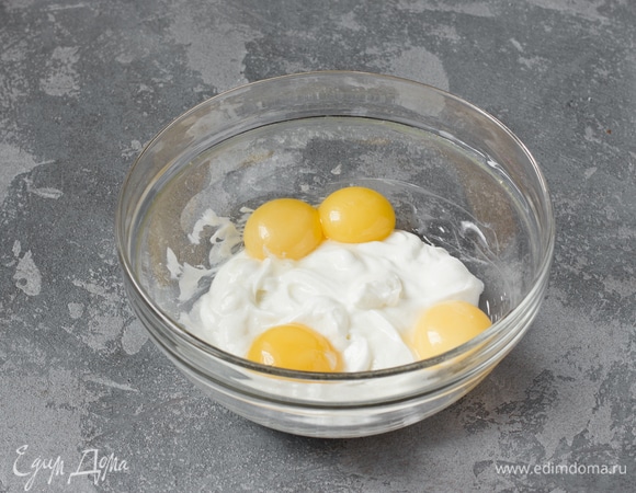 После того как сыворотка стечет, в марле должно остаться 220 г густой йогуртовой массы. Переложить ее в глубокую миску. Добавить туда же 40 г сахара и яичные желтки, перемешать силиконовой лопаткой до получения однородной массы.