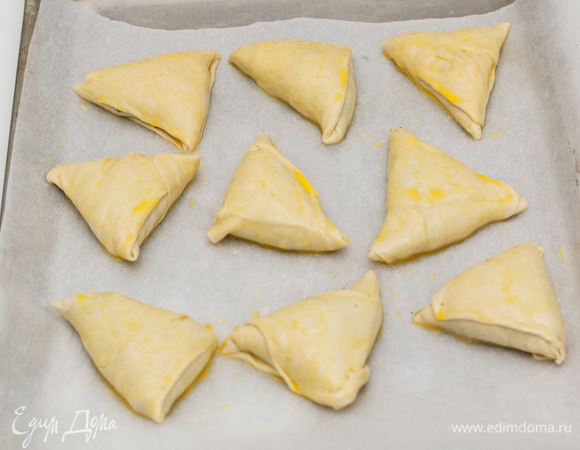 Подготовленные пирожки уложить на противень, смазать желтком и выпекать 20–25 минут при температуре 180°C.