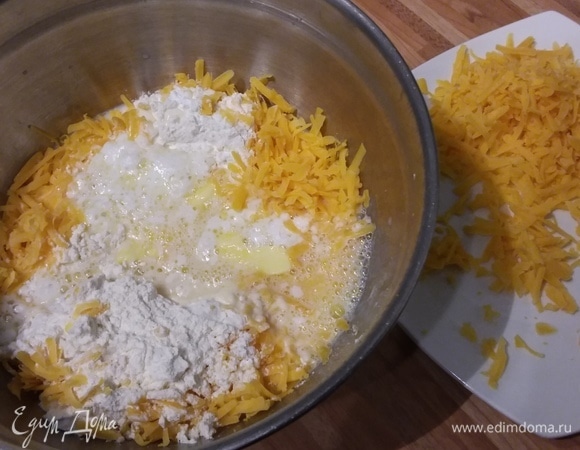 Для сконов сыр чедер (можно использовать любой другой) натереть на терке. 25 г сыра отложить в сторону, он понадобится для финальной посыпки. Соединить в миске муку, разрыхлитель, соль, молоко, размягченное сливочное масло и 100 г сыра.