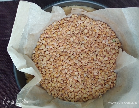 Наколоть тесто вилкой, сверху прикрыть бумагой для выпечки и насыпать фасоль или горох для груза. Выпекать 15 минут в разогретой до 180°C духовке. Убрать груз и допечь еще 5 минут.