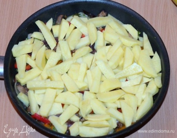 Очищенный от шкурки и порезанный картофель, солим и перчим. Периодически перемешиваем и готовим до готовности мяса и картофеля.