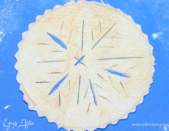 Раскатываем слоеное тесто на припыленной мукой доске и вырезаем 4 круга, диаметр которых должен быть на 2 см больше диаметра формочки. На круге можно вырезать снежинки.
