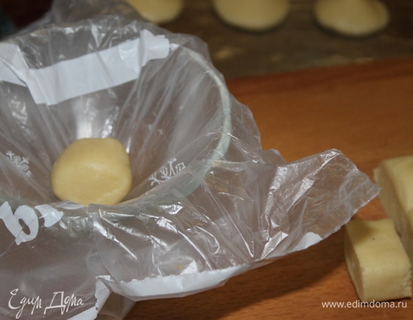 В чашу миксера положите мягкое масло, сметану, сахар и яйцо. Объедините все в однородную смесь и добавьте муку с разрыхлителем (заменила гашеную соду). Долго тесто не месите, достаточно, чтобы оно стало однородным. У вас получится мягкое, но не липкое тесто. Заверните его в пакет и положите минимум на час в холодное место. Оно должно хорошо застыть. Разделите тесто на 4 части и каждую часть берите из холодильника по мере необходимости. Из 1/4 части мы сделаем ножки, а из остального теста будем делать шляпки. Разделите тесто для шляпок на порции, чтобы у вас получился шарик размером с грецкий орех. Шляпки можно формировать руками, я использую подходящую по форме креманку, застелив ее пленкой.